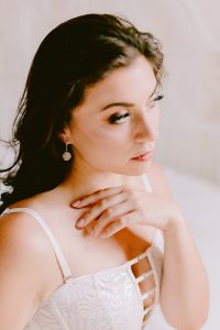 Styled boudoir photo featuring dark haired caucasian model with white lingerie and white druzy earrings made by J'Adorn Designs