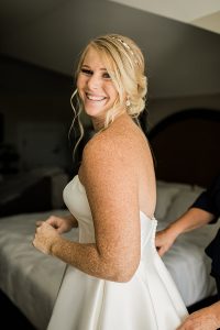 Smiling blonde bride in sparkly gold bridal teardrop earrings by J'Adorn Designs bridal jeweler for a classic Annapolis wedding at Chesapeake Bay Beach Club