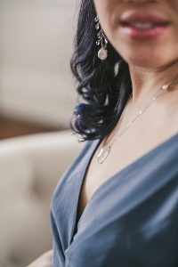 Close up photo of a rose gold necklace with a crystal quartz pendant and freshwater pearl accent. Handcrafted jewelry for maternity photos by J'Adorn Designs