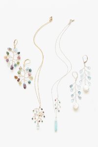 Flat lay photo of a rainbow colored jewelry set of earrings and necklaces. Delicate botanical jewelry designs by J'Adorn Designs artisan jeweler Alison Jefferies. Handcrafted jewelry and luxury bridal accessories made in Maryland.