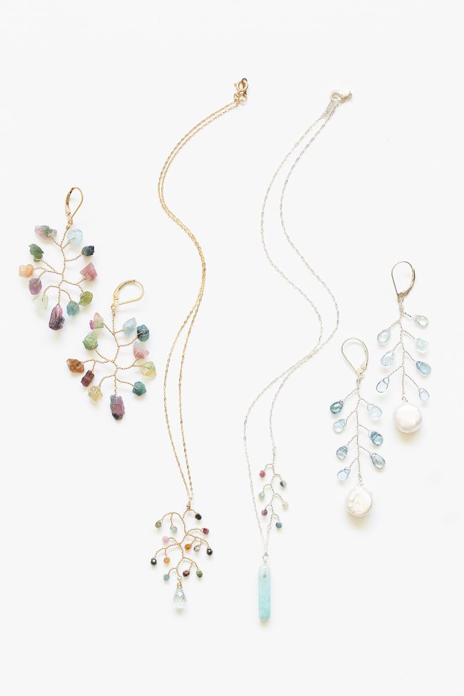 Flat lay photo of a rainbow colored jewelry set of earrings and necklaces from The Prism Collection. New delicate botanical jewelry designs by J'Adorn Designs artisan jeweler Alison Jefferies. Handcrafted jewelry and luxury bridal accessories made in Maryland.